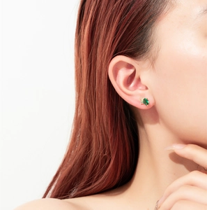 Close-up of elegant gold pear-cut emerald stud earring on model's earlobe