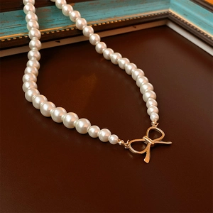Collier de perles vintage français avec fermoir nœud doré sur fond sombre élégant