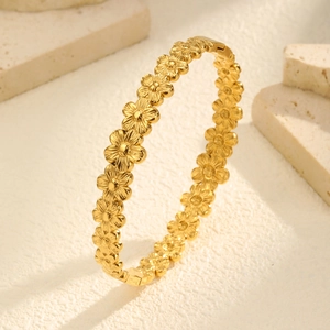 Detailed view of the gold hollow floral pattern and clasp on the stainless steel bangle
