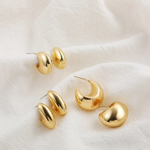 Three sizes of 18K gold hollow teardrop earrings arranged on white pleated linen fabric