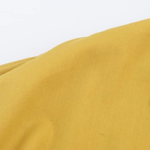 Gros plan sur le tissu jaune en popeline de la robe midi montrant le tissage serré du coton