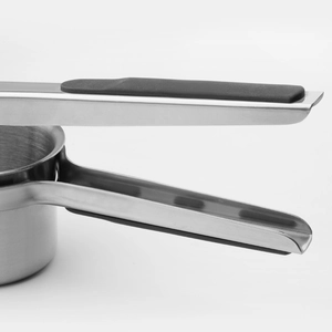 Stainless steel potato ricer with ergonomic black silicone handle on white background