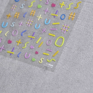Macro shot of 5D embossed nail art stickers with 3D macaron letters and symbols