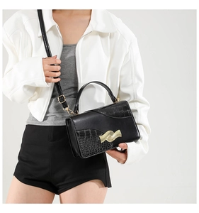 Detail of square handbag showing smooth leather and crocodile pattern texture with gold hardware