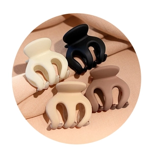 Set of 4 matte mini hair clips in cream, black, beige, and brown on soft pink fabric