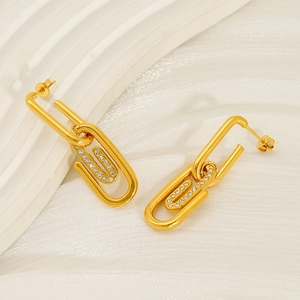 Boucles d'oreilles trombone dorées avec pavé de zircons sur fond de soie blanche