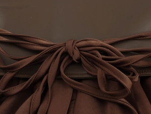 Detail view of the brown satin bow tie and premium leather texture on women dress waist