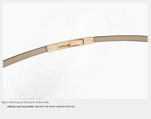 Detail of thin beige patent leather belt showing stitching and gold rectangular buckle