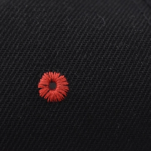 Makroaufnahme der roten Gänseblümchen-Stickerei auf schwarzem Twill-Stoff der Kappe