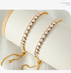 Close-up of adjustable gold tennis bracelets with sparkling cubic zirconia on a white stand