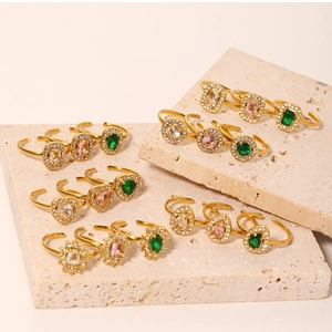 Detail of vintage gold rings with emerald and zircon stones on travertine stone