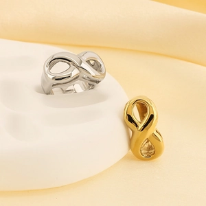 Minimalist 18k gold and silver infinity rings on elegant fabric background