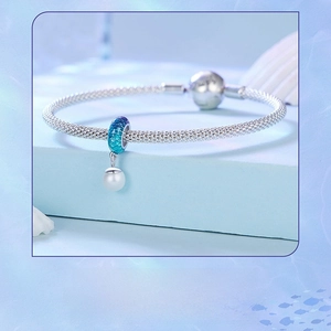 Close-up of S925 blue gradient fish scale bead and pearl charm on a woven silver bracelet