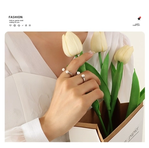 Detailed view of two baroque pearl rings on hand featuring an elegant U-shape design