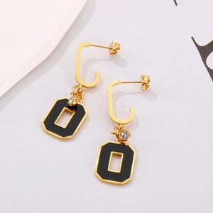 Close-up of geometric black and gold earrings with white crystal and titanium steel