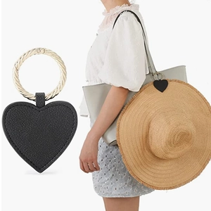 Detail of heart-shaped black leather hat clip with golden ring for travel bag hanging