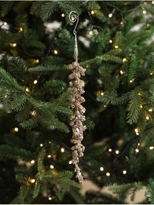 Close-up of glittery rose gold icicle ornament with beads on a Christmas tree branch