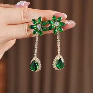 Macro shot of green zircon flower and teardrop earrings with golden alloy plating