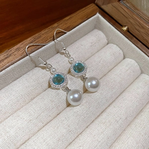 Dettaglio orecchini con gemma blu con alone di diamanti e perla bianca pendente