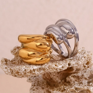 Detailed view of textured 18K gold and silver water wave dome rings on a stone base