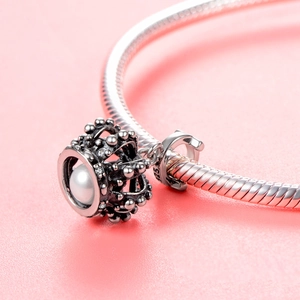 Macro shot of 925 sterling silver crown pendant with white pearl and inlaid gemstones