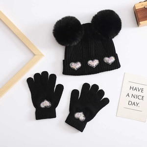 Detail of baby winter knit hat with pom-poms and gloves featuring sequin heart patches