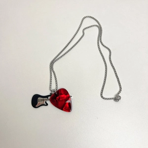 Detail of red translucent guitar pick and black mini guitar pendant on silver chain