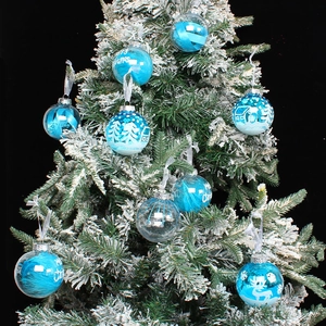 Transparent blue Christmas ball ornaments with feathers hanging on a snowy Xmas tree