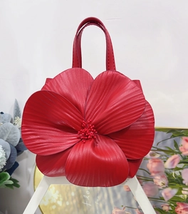 Detailed close-up of a red flower-shaped leather handbag with beaded pistil and petal textures