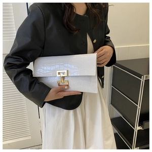 Detailed view of white crocodile pattern envelope clutch bag with gold metal hardware