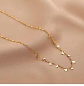 Macro view of gold droplet pendant necklace on soft satin fabric, bohemian jewelry style
