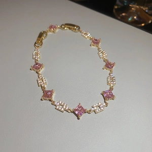 Detail of gold butterfly bracelet featuring pink square stones and shimmering crystal pavé