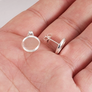 Pair of silver stainless steel earring bezel settings held on a hand for DIY jewelry