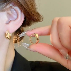 Close-up of a gold geometric faceted hoop earring worn on the ear for a stylish look