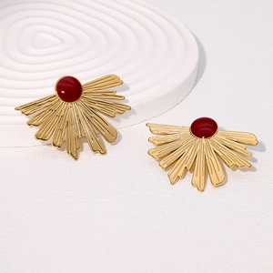 Detailed close-up of fan-shaped golden earrings with a deep red center on a white background