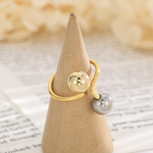 Minimalist gold bypass ring with metallic beads on a wooden display cone