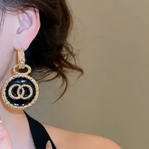 Orecchini vintage rotondi in smalto nero e oro con bordi testurizzati e motivo CC
