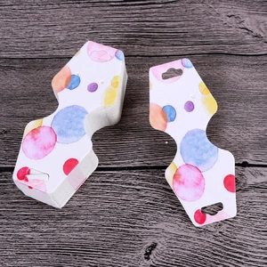 Macro view of watercolor polka dot paper jewelry display cards on a dark wood background