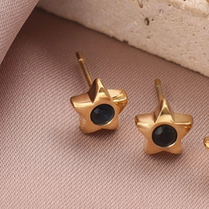 Vue macro de boucles d'oreilles étoiles dorées avec pierre bleue sur fond de pierre