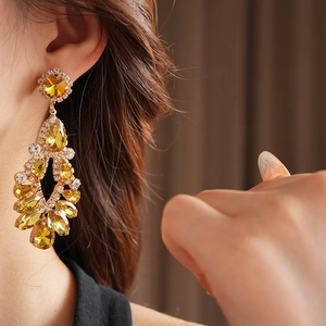 Macro detail of luxury teardrop tassel earrings with yellow crystals and rhinestones