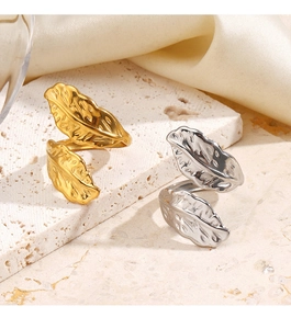 Macro detail of gold and silver feather rings on stone with champagne silk background