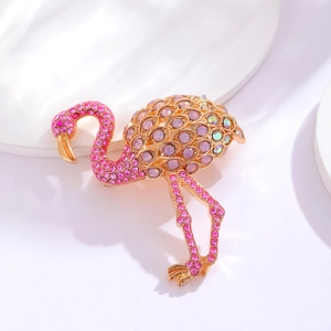 Pink rhinestone flamingo brooch in gold plating on a minimalist white display