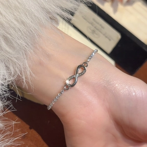 Macro detail of infinity symbol bracelet with sparkling micro-pave zircons on a silver chain