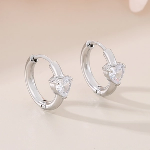 Detailed macro view of heart-shaped cubic zirconia stones on silver stainless steel hoop earrings