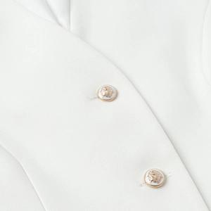 Detailed close-up of premium white twill fabric with decorative gold crest buttons