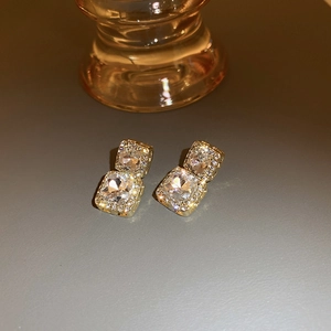 Macro shot of double layered gold square earrings with sparkling crystal pavé stones