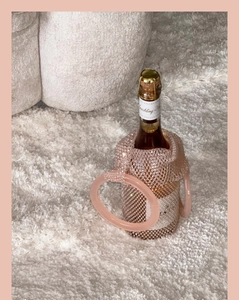 Close-up of pink handmade beaded wine bag with elegant round handle on soft carpet
