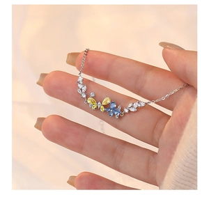 Detail of silver butterfly pendant with blue and yellow gems on delicate chain