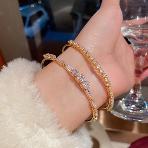 Macro view of layered 18K gold plated bracelets featuring sparkling cubic zirconia stones