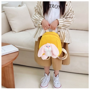 Yellow toddler backpack featuring a 3D plush long-eared bunny toy shown in a home setting
